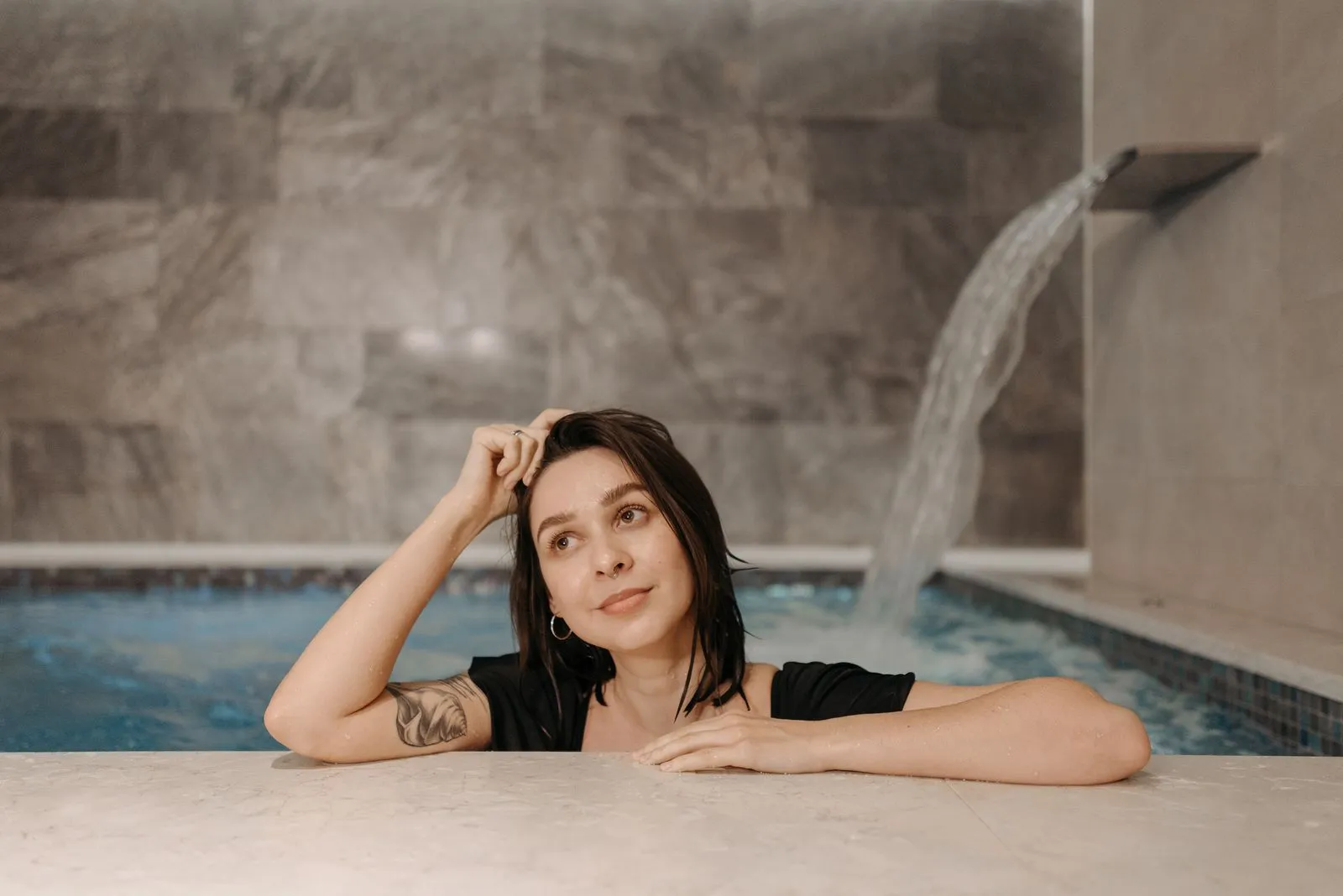 Woman relaxing by an indoor pool, enjoying a serene and calm moment.